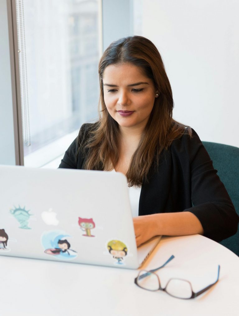 Professional woman focused on laptop work in a modern office setting.